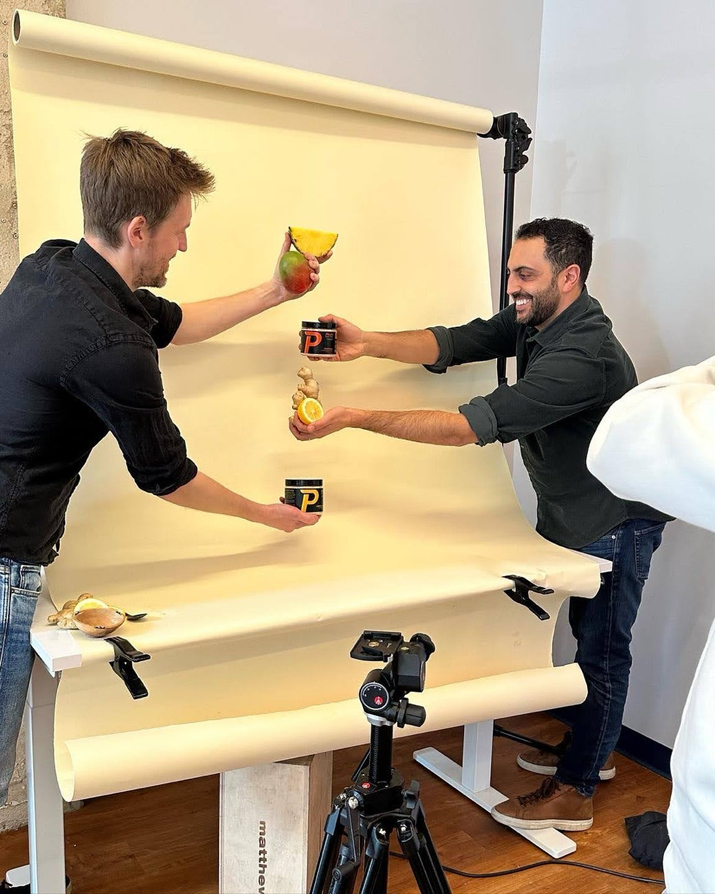 Matt and Jason, the two founders of Pinch, at a product photoshoot holding jars of Pinch with fresh ginger, lemon and mango